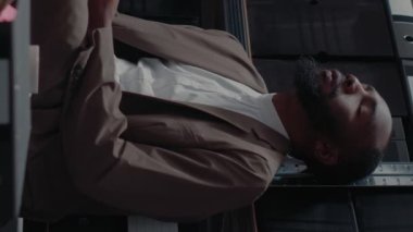 Dikey video: Müfettişler iş arkadaşları ofiste arşiv kayıtlarını okuyor, yerde oturuyor, suç işleme üzerinde çalışıyorlar. Dedektiflerden oluşan bir ekip güvertedeki güvenlik kamerası fotoğraflarını ve kanıt haritasını inceliyor.