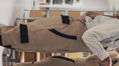 Dikey video: Raflarda ürün düzenleyen, stok lojistiğini kontrol etmek ve dağıtımı planlamak için tablete bakan iki kadın. Depo müdürü ve çalışanı karton paketleri sayıyor.