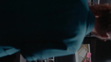 Dikey video: Dava dosyalarında geçmiş kontrolü kullanarak suç faaliyetlerini çözmek için ipuçları ve araştırmalarla kurulu inceleyen kadın dedektif. Gözetim fotoğraflarına bakan bir kadın. El bilgisayarı