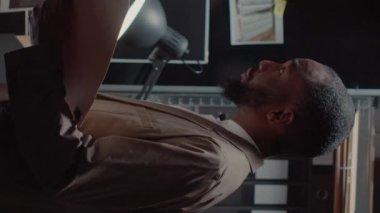 Dikey video: Dedektif meslektaşlar ofiste suç dosyalarını inceliyor, gözetim fotoğraflarına bakıyor. Polis memurları kanıt haritasını inceliyor soruşturma yürütüyor, kayıtlara işaret ediyor.