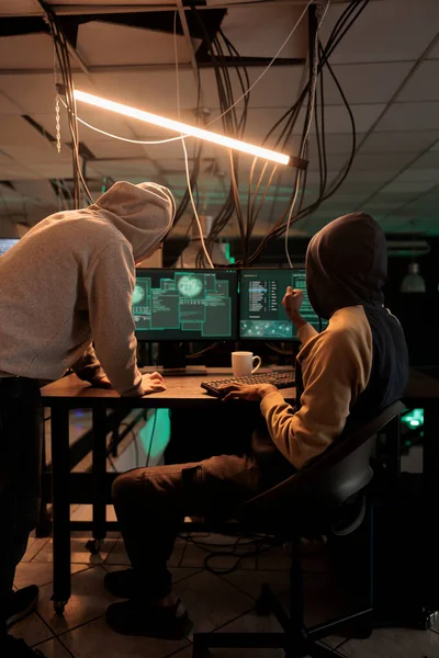 サイバー犯罪者のチームは 夜に政府システムをハックするためにウイルスを使用して ファイアウォールの暗号化を解読しようとします パスワードや機密情報を盗むためにデータベースに侵入する若い男性 — ストック写真