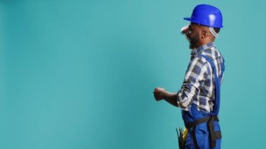 Afro-Amerikan marangoz çekiçle duvarlara vuruyor, elle yenileme ve yeniden yapılanma işi için alet kullanıyor. Tulumlu erkek inşaatçı, kaya matkabı tekir aleti tutuyor..