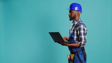Modern inşaatçı projeye ilham bulmak için dizüstü bilgisayar kullanır, çevrimiçi gezinir ve kamera üzerinde hesaplamalar veya ölçümler yapar. Çalışmak için kablosuz bilgisayar tutan inşaat işçisi.