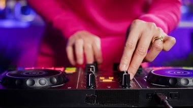 Dj artist creating unique techno sound using mixer console, performing at eletronic party in club at night. Asian musician playing remix song using professional audio equipment. Music concept