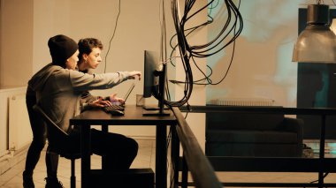 Cyber criminals working with dark web to do illegal hacktivism on online network, trying to steal information illegally. Team of people breaking into server for cyberwarfare. Handheld shot.