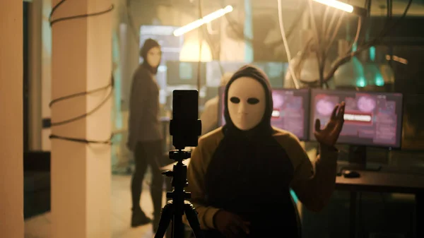 暗いWeb上でライブランサムウェアビデオを記録し パスワードを盗んだ後に脅威を作り出す白いマスクを持つ熟練したサイバー犯罪者 マスクハッカーは夜にカメラで神秘的な演技 ハラスメント — ストック写真
