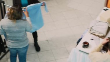 Moda mağazalarındaki modern kıyafetleri analiz eden çeşitli müşteri grupları, moda markalarındaki satışları kontrol ediyorlar. Giyim mağazası müşterileri alışveriş merkezinden, küçük işletmelerden mal alıyorlar. El kamerasıyla..