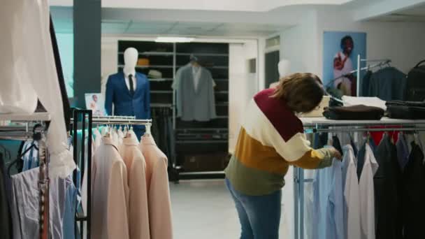 アフリカ系アメリカ人女性のショッピングモールでは ファッションブティックの商品を見て正式な服を購入し ワードローブを改善する ラック上の製品の女性クライアントチェックファブリック — ストック動画