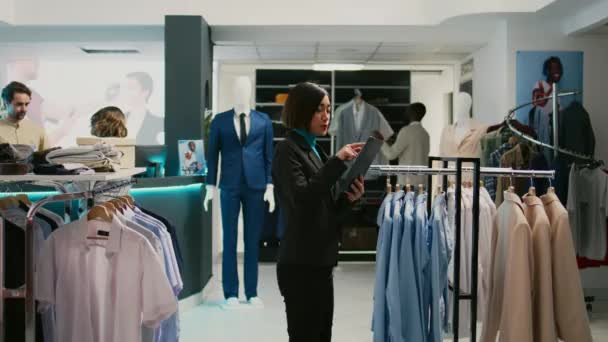 Aziatische Winkel Assistent Analyseren Voorraad Opgehangen Kleding Het Doen Van — Stockvideo