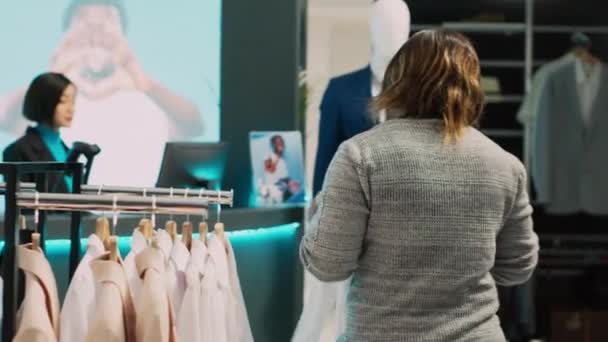 アフリカ系アメリカ人のクライアントは 商品を購入する前に流行の服でドレスアップしようと 店でフィッティングルームを見つけようとしています 市場での正式な摩耗に適合しようとしている現代の女性 手持ち撮影 — ストック動画