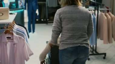 Engelli Afrikalı Amerikalı bir adam perakende dükkanını ziyaret ediyor. Moda koleksiyonu için giyim mağazasından alışveriş yapıyor. Tekerlekli sandalyedeki bir erkek, market mağazasından günlük kıyafet alıyor..