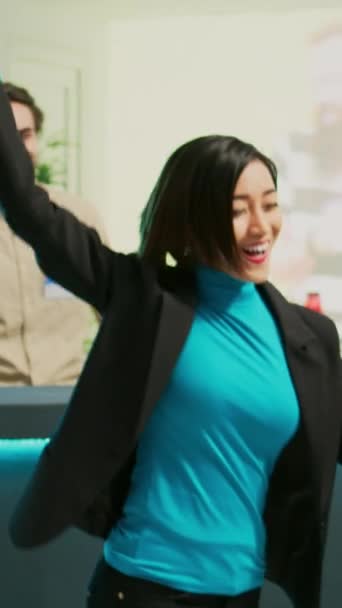 垂直ビデオ 若いクライアントは 衣料品店から買い物袋を支払った後に踊る ショッピングセンターで陽気なショッピング製品を感じている ファッションショールームでダンスムーブを示すアジアの女性 — ストック動画
