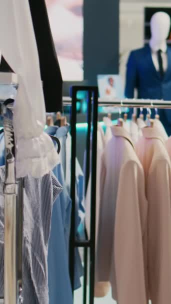垂直ビデオ 現代人やクライアントのための空の衣料品店 ファッションブティックショップで服と商業活動 ショッピングセンターでのカジュアルウェアの近代的なトレンディーな新しいコレクション — ストック動画