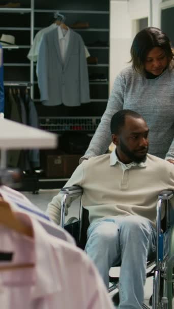 Dikey Video Tekerlekli Sandalyedeki Erkek Kullanıcı Moda Mağazasından Moda Giysileri — Stok video