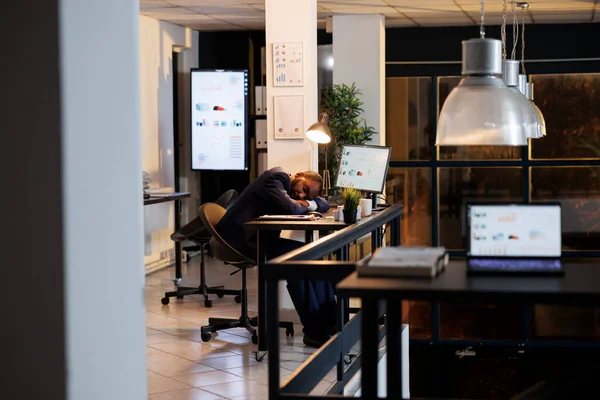 非洲裔美国人经理因为在新成立的办公室工作超负荷而在办公桌上打瞌睡 工作倦怠的商人在公司投资计划的深夜工作后睡着了 业务概念 — 图库照片