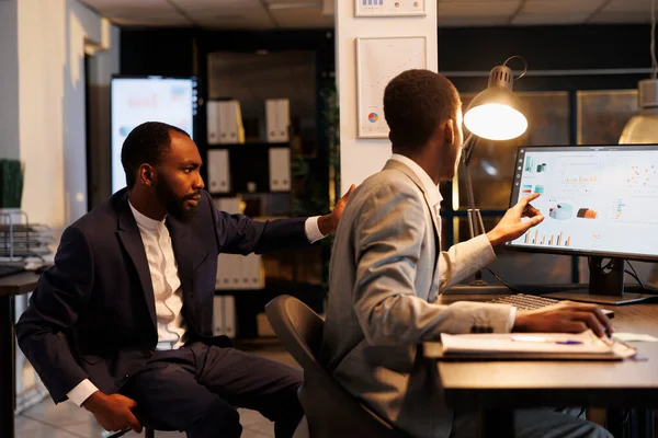 非裔美国人同事分析营销策略 讨论财务增长报告 深夜在公司创业办公室工作 管理团队规划业务研究计划 — 图库照片