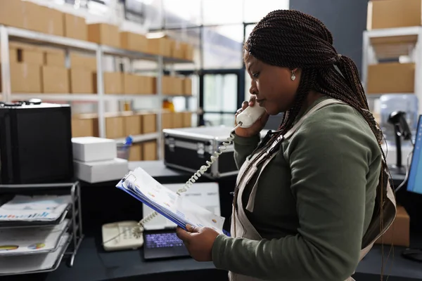 Αφροαμερικάνος Εργάτης Μιλάει Στο Σταθερό Τηλέφωνο Απομακρυσμένο Πελάτη Συζητώντας Λεπτομέρειες — Φωτογραφία Αρχείου