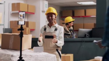 Sosyal medya için halkla ilişkiler videosu çeken Afro-Amerikalı bir kız kutular içinde depo için reklam yapıyor. Akıllı telefondan video kaydeden kadın, hisse senedi ticareti. El kamerasıyla..
