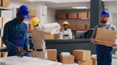 Genç erkek işçiler, barkodları taramak ve emirler göndermek için tarayıcı kullanarak paketleri kontrol ediyorlar. Karton kutularda iş dağıtımı yapmayı planlayan insanlardan oluşan bir ekip..
