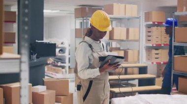 Barkodları tarayan, karton kutularda paketlenmiş ürünlere bakan çok ırklı işçiler. Erkek çalışan, malları denetleyiciye getiriyor, sevkiyat planlıyor..