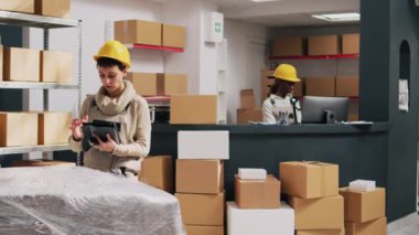 Erkek işçi denetçiye mal veriyor, kutulardaki barkodları taramaya yardım ediyor ve ürünler için stok lojistiği planlıyor. Tarayıcı ve tabletle ürünleri tarayan iki kişi.