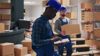 Çeşitli çalışanlar depo alanındaki ürün paketlerini inceliyor, sevkiyat için envanter sayımı yapmak üzere kutulardaki barkodları tarıyor. Perakende ürünlerle çalışan işçi ve yönetici..
