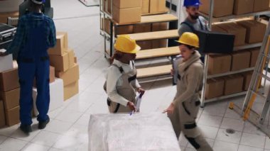 Çeşitli kadınlar depoda sevkiyat ve teslimattan bahsediyor. Stok lojistiği listesini inceliyorlar. Endüstriyel ürünler ve ürün paketleriyle çalışan gençler, depo. Üçayak atışı.