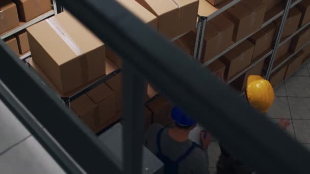 非裔美国人在仓库里使用笔记本电脑和平板电脑 用纸板箱包装商品 仓库员工检查货架和货架 运送货物 — 图库视频影像