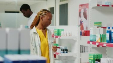 Perakende satış mağazasında tıbbi ürünleri analiz eden kadın müşteriler eczanede ilaç ve sağlık ilaçları arıyorlar. Genç bir kadın ilaç ve ilaç paketlerini kontrol ediyor..