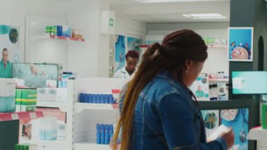 Man and woman looking for healthcare products in pharmacy, checking packages of medicaments and supplements. People buying prescription treatment or vitamins bottles. Tripod shot.