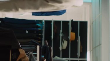 Dikey video: Afrikalı Amerikalı bir adam askı için resmi kıyafet almak isteyen gömlekler için asistanından yardım istiyor. Perakende mağazası çalışanı müşteriyle şık kıyafetler alışverişi hakkında konuşuyor.