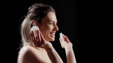 Güzel pamuklu pedlerle poz veren komik doğal bir kadın stüdyoda gülüyor, kamerada kocaman bir gülümseme gösteriyor. Mutlu pozitif kız kozmetik ürünleri ve cilt ürünleriyle aptalca davranıyor, güzellik reklamı..