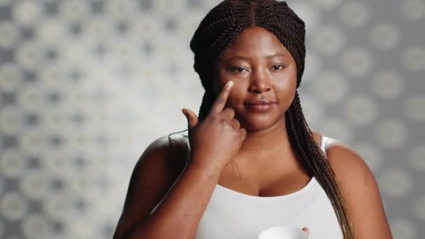 非裔美国人模型应用于面颊上的抗衰老面霜 促进保湿和血清以防止皱纹 光彩夺目的女性为护肤产品做广告 — 图库视频影像