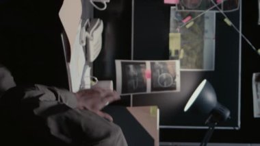 Dikey video: Afro-Amerikan ajanları gözetim fotoğraflarını inceliyor, olay odasında adli soruşturma üzerinde çalışıyor. Dedektiflerden oluşan bir ekip gemide adli delilleri inceliyor.