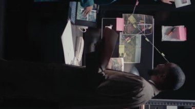 Dikey video: İki müfettiş kanıt odasındaki arka plan kayıtlarını kontrol ediyor, özel soruşturma için güvenlik görüntülerine bakıyor. Harita ve dava dosyalarında ayrıntıları ortaya çıkaran polis memurlarından oluşan bir ekip.