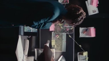 Dikey video: Polis ajanları olay odasındaki sabıka kayıtlarını inceliyor, soruşturma için şüpheli fotoğraflara bakıyor. Soruşturma dosyalarındaki ipuçlarını analiz eden genç dedektifler.