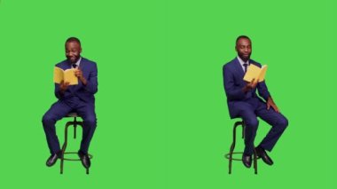 Olumlu bir çalışan stüdyoda oturup, yeşil ekran arka planında edebiyat okumaktan mutlu oluyor. Sandalyedeki genç işadamı elinde roman dersi tutuyor..