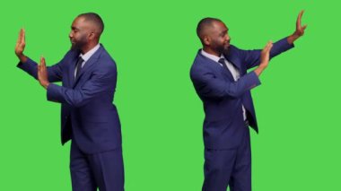 Erkek çalışan sol ya da sağ tarafa bir şey itiyor, objeyi yandan reddediyor ve yeşil ekranın arkasında duruyor. İş adamı inkar ediyor ve stüdyoda reddediyor..