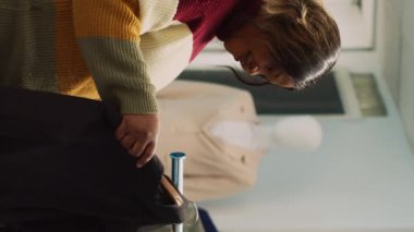 Dikey video: Afrikalı Amerikalı müşteri resmi kıyafet alışverişi yapıyor, yeni perakende mağaza ürünlerini inceliyor. Giyim mağazasında moda butiği kıyafetlerini kontrol eden genç bir kadın, ticari faaliyetler