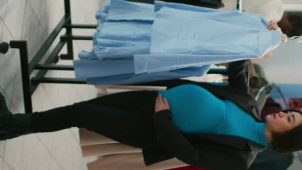 垂直ビデオ モールのデパートで服のための赤ちゃんバンプショッピングを持つアジアの女性は ハンガー上の新しいファッションブランドを見て 若い将来の母親が妊娠中のショッピングセンターを訪問 — ストック動画