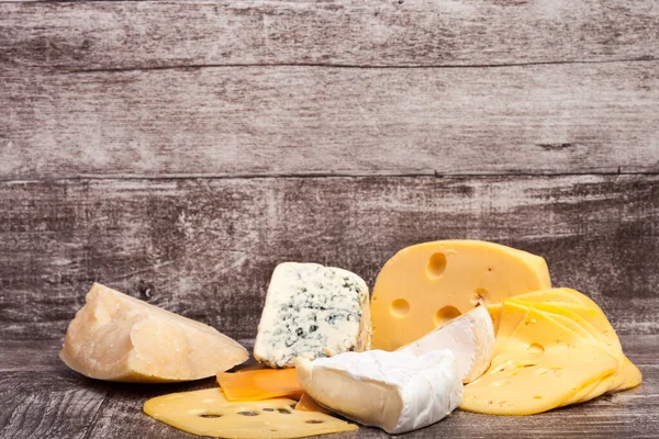 木制背景的不同类型的奶酪 味道鲜美食品清新剂 — 图库照片