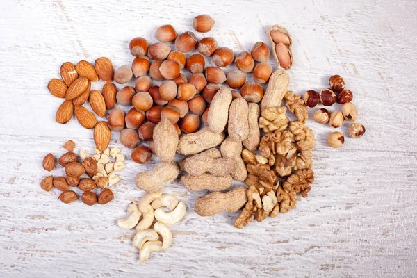 Mix of variety of nuts on white wooden background. Healthy raw snaks