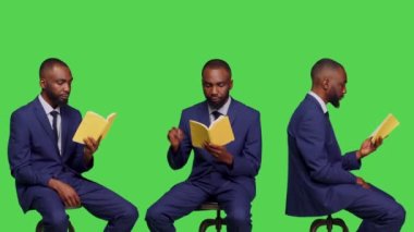 Afro-amerikan kişi, yeşil ekran arka planında oturan, hikaye kitabının sayfalarını okuyor. Ofis çalışanı takım elbise içinde edebiyat romanı okumaktan mutlu, kendinden emin bir adam..