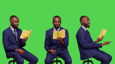 Ofis çalışanı kamerada edebiyat kitabı okuyor, takım elbise giyiyor stüdyoda sandalyede oturuyor. Kendine güveni olan kişi yeşil ekran arkaplanının üzerinde poz vererek roman veya kurgu hikayesinden zevk alıyor..