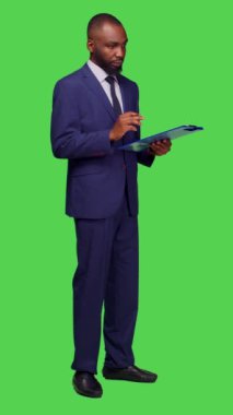 Dikey video: Kamera üzerinde yeni bilgiler düşünen, fikir üreten ve pano dosyaları üzerine notlar alan başlangıç yöneticisinin yan görüntüsü. Şirket çalışanı takım elbise giyiyor ve...