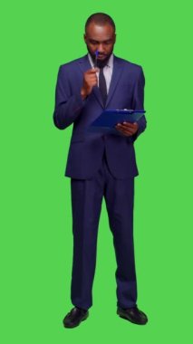 Dikey video: Kamera üzerinde yeni bilgiler düşünen, fikir üreten ve pano dosyaları üzerine notlar alan başlangıç yöneticisinin ön görüntüsü. Şirket çalışanı takım elbise giyiyor ve...