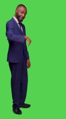 Dikey video: Takım elbiseli erkek çalışanın tabela takıp, izole edilmiş yeşil perde arkasında poz vermesi. Yeni başlayan işçi insanları arıyor, katılmak ya da eşlik etmek istiyor