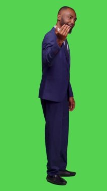 Dikey video: Takım elbiseli erkek çalışanın profili buraya gelip izole edilmiş yeşil perde arkasında poz veriyor. Yeni başlayan işçi insanları arıyor, katılmak ya da eşlik etmek istiyor