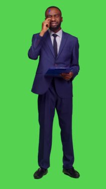 Dikey video: Kamera üzerinde yeni bilgiler düşünen, fikir üreten ve pano dosyaları üzerine notlar alan başlangıç yöneticisinin ön görüntüsü. Şirket çalışanı takım elbise giyiyor ve...