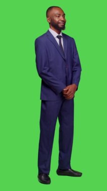 Dikey video: Girişim yöneticisinin kamerada kendine güveni, şirket işinde çalışmak için takım elbise giymesinin yan görüntüsü. Gülümseyen yetişkin girişimci yeşil ekran tüm vücut arka planı üzerinde poz